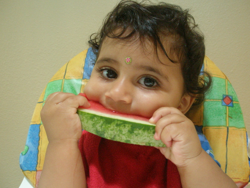 The original photo: a toddler eating a slice of watermelon in a high chair