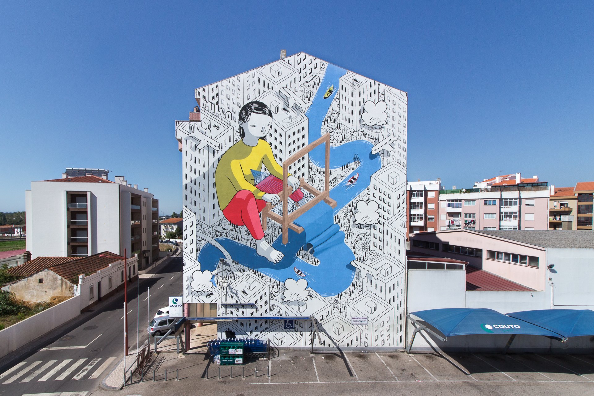 Weave, a Millo mural in Estarreja, Portugal — a figure at a traditional loom, painted across the side of a building.